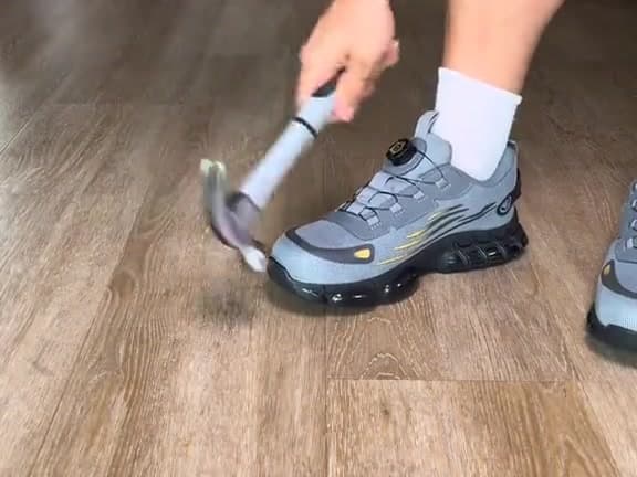 Martillo golpeando la puntera de acero de una zapatilla de seguridad